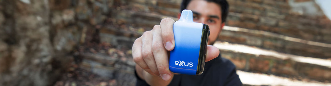 Woman holding Exxus Vape in front of warehouse