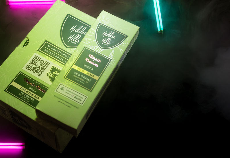 Hidden Hills Bussin Blend 2g Live Rosin Disposable 5pk laying on black table with neon lights and smoke surrounding the pack